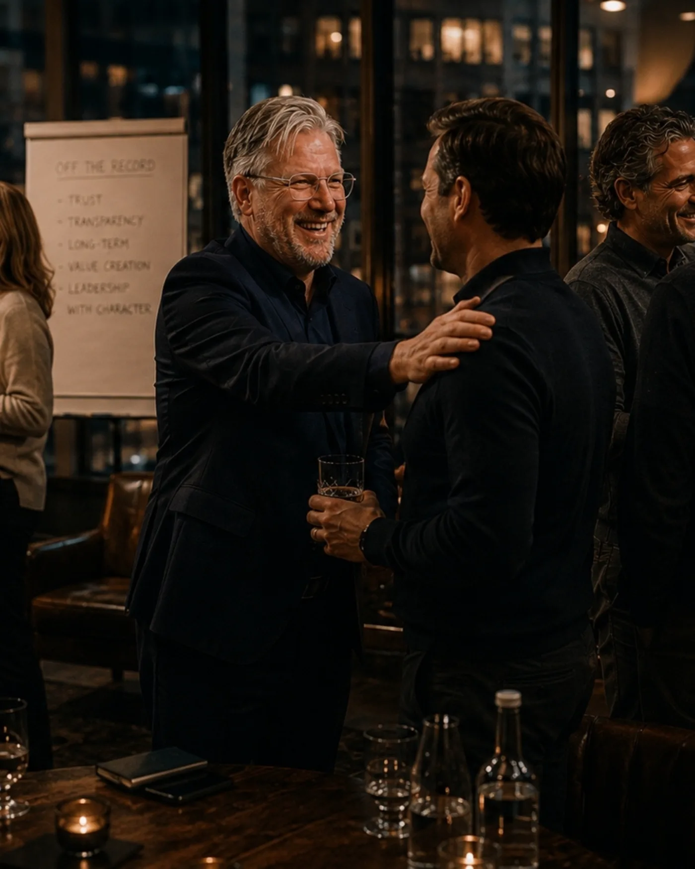 Twee commercieel leiders in gesprek tijdens een avondbijeenkomst van Salesbazen, met op de flipover achter hen de uitgangspunten vertrouwen, transparantie, lange termijn, waardecreatie en leiderschap met karakter.