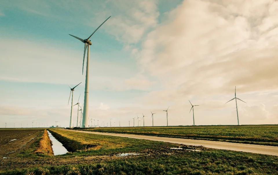 Een windturbine in een open veld tegen een bewolkte lucht.